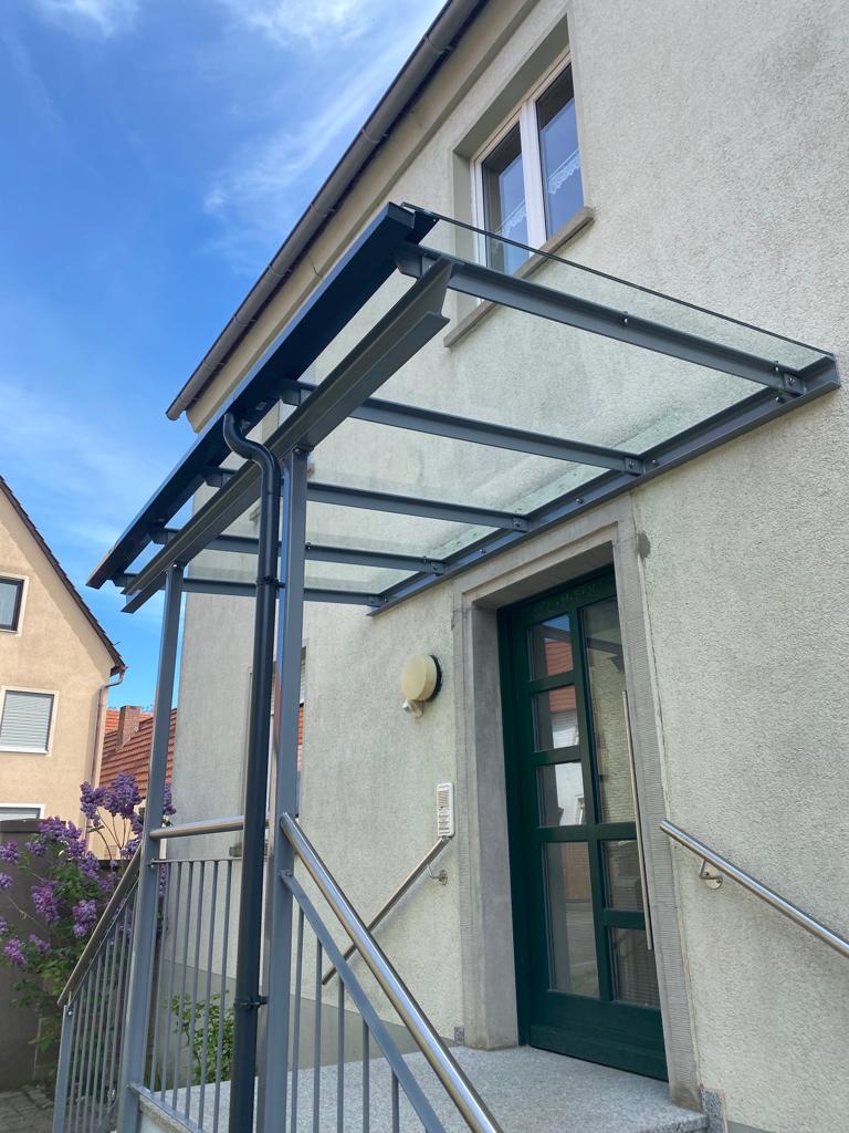 Überdachung aus Metall mit Glasdach und Regenrinne, perfekt integriert in das Treppengeländer